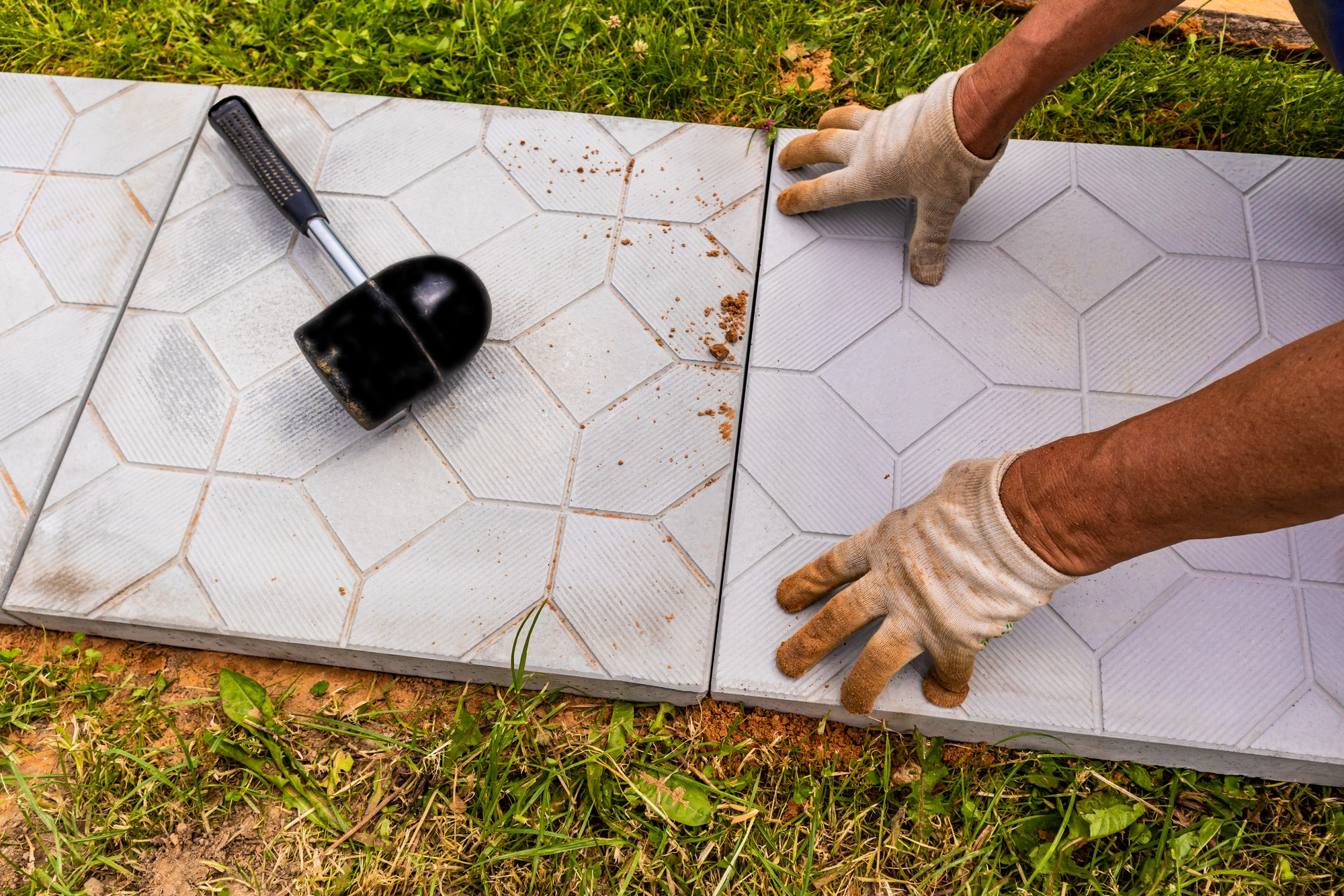 the hands of a worker in gloves lay tiles in a country house. Landscaping. laying of stone tiles.